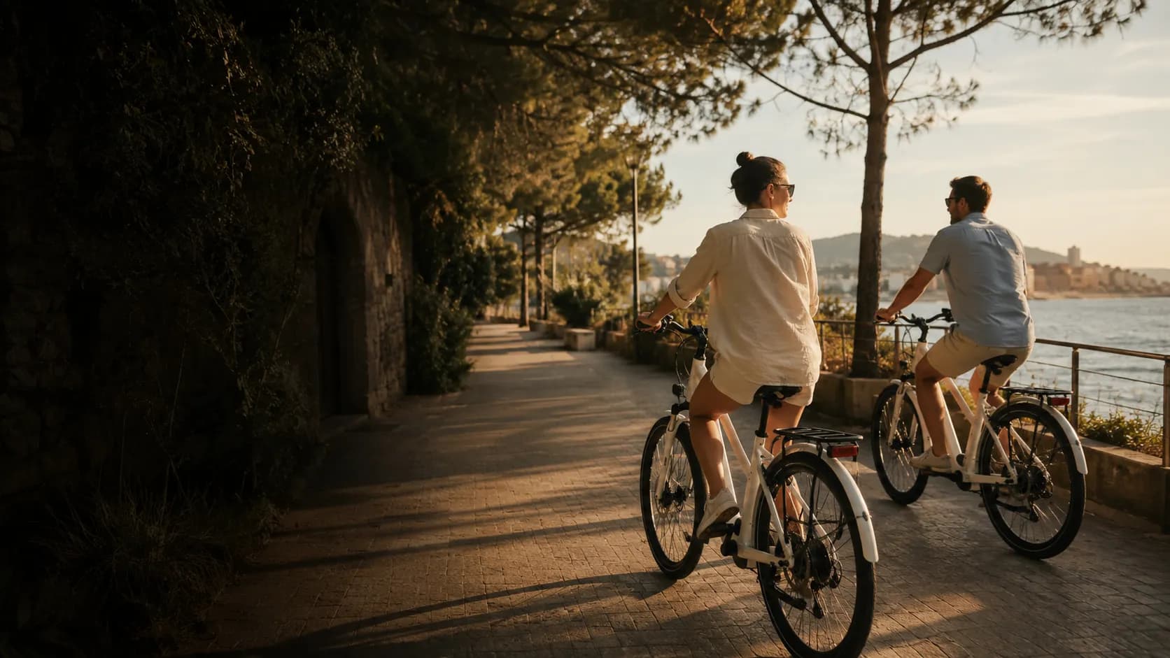 Two travelers on a private e-bike tour along a Mediterranean coastal path in Barcelona at golden hour